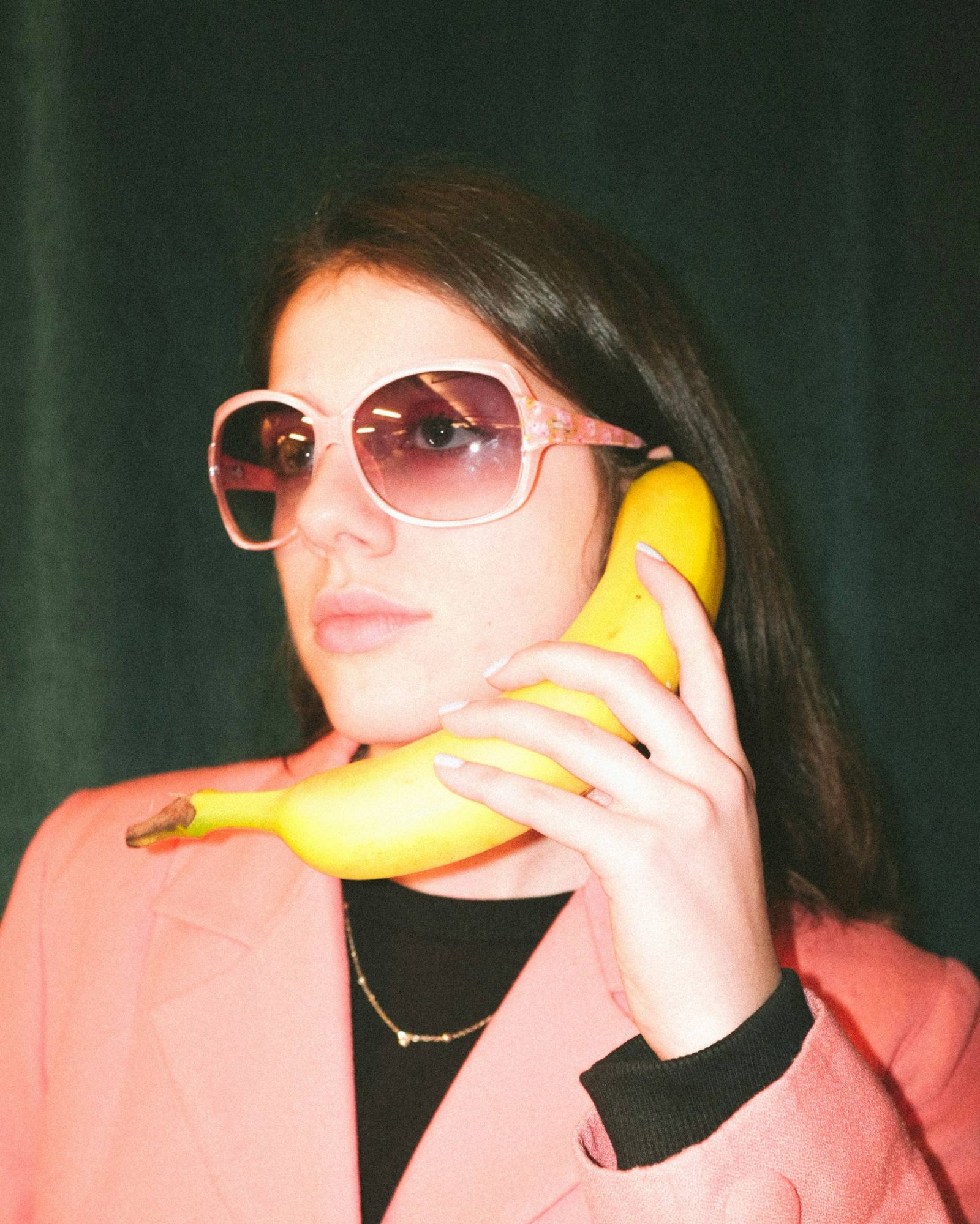 Retro photo of young college woman holding a banana like a telephone.