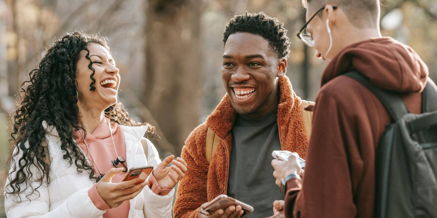 Group of friends outside holding phones and laughing