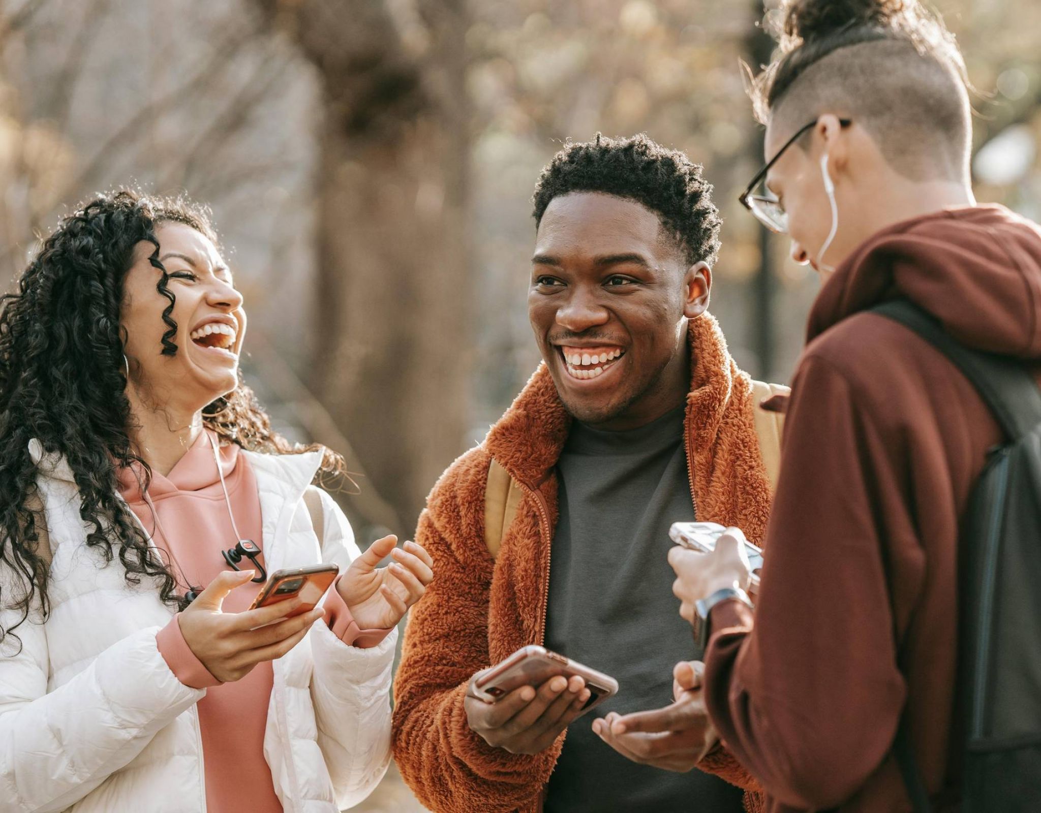 Group of friends outside holding phones and laughing