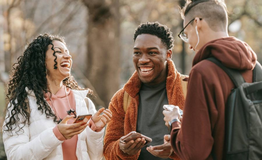 Group of friends outside holding phones and laughing