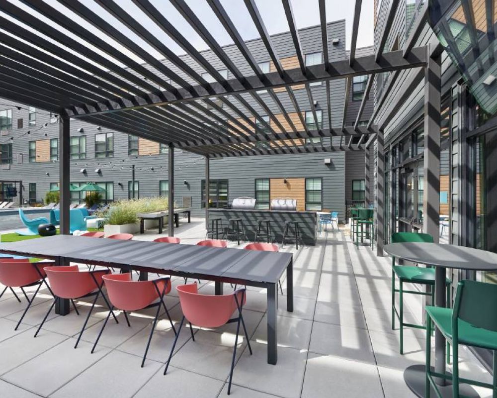 An outdoor courtyard at VERVE Boise with modern dining tables, shaded by sleek pergolas, offering a relaxing space.
