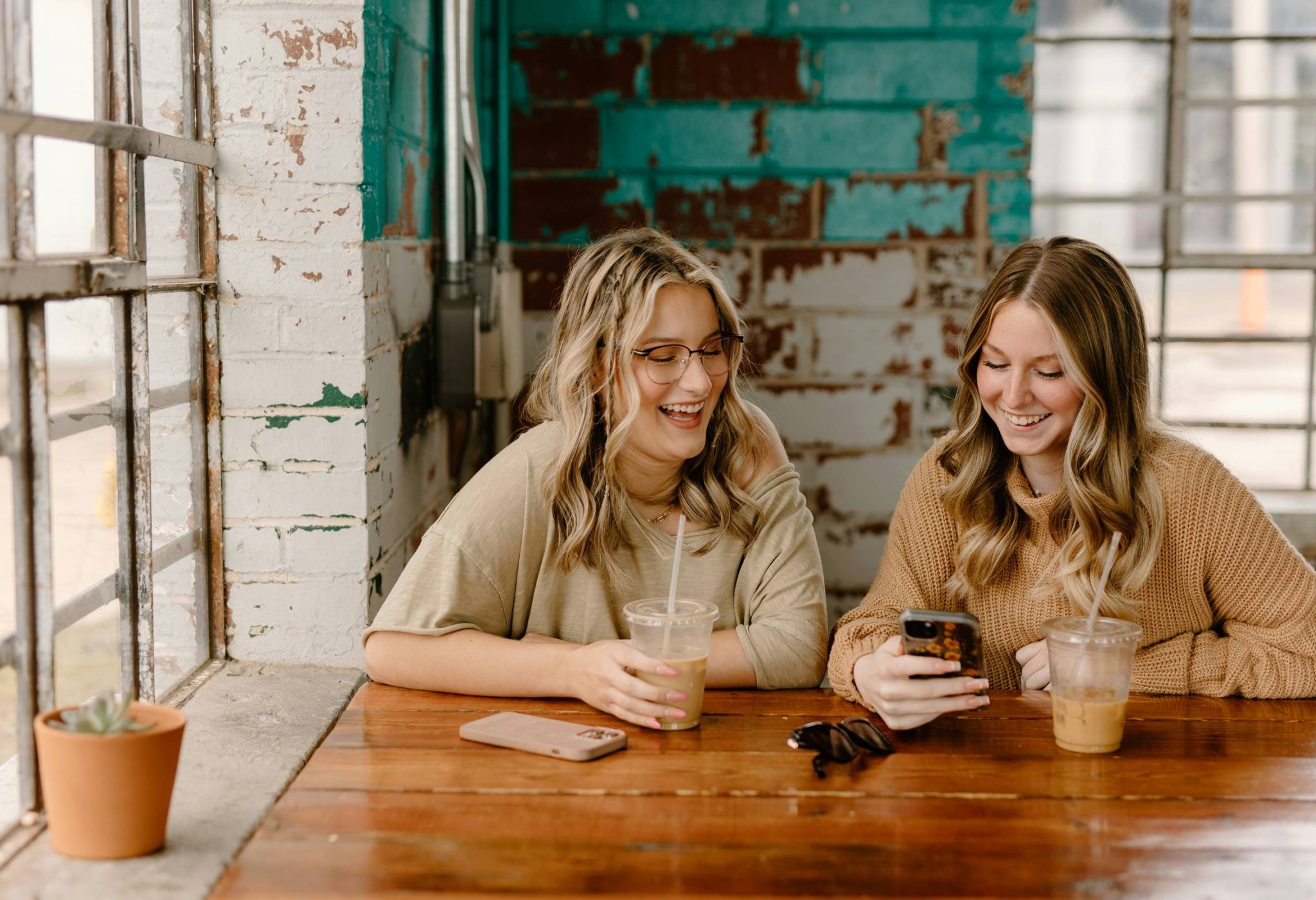 Two young women looking at phone at coffee shop