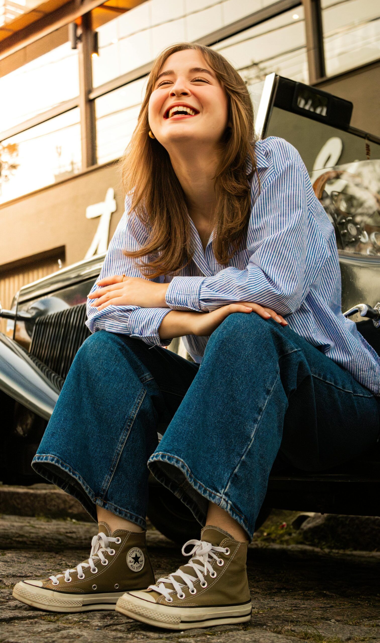Happy young woman in city sitting on step.