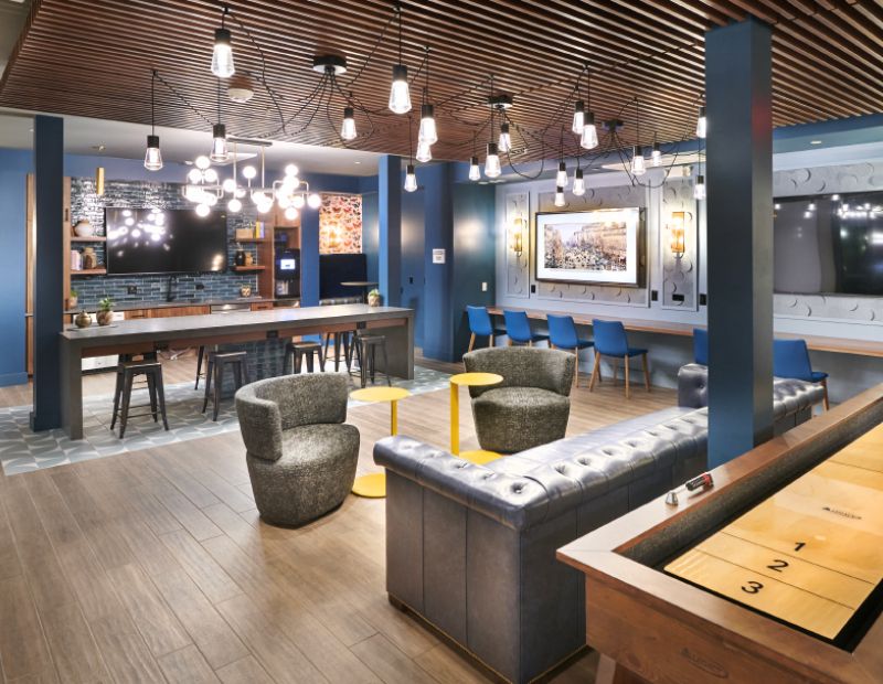 A stylish kitchen and bar area at VERVE Boise, complete with blue walls, a tiled backsplash, and a modern chandelier.
