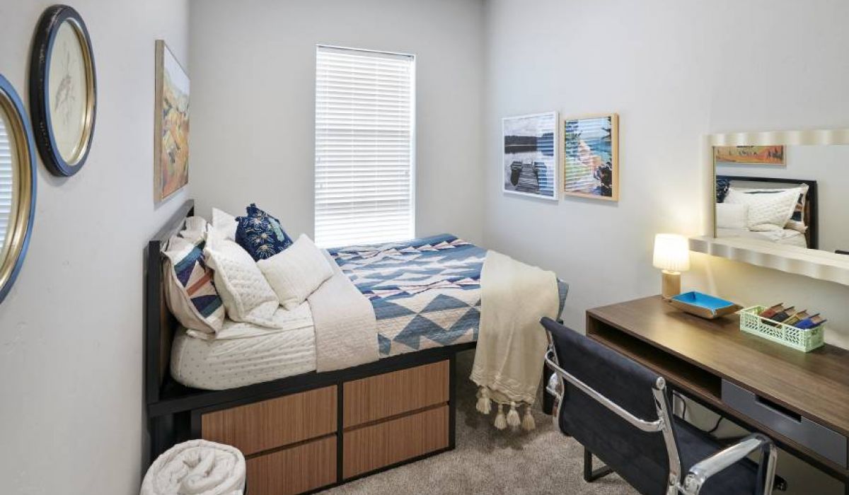 A second bedroom in VERVE Boise featuring a twin bed with under-bed storage, a desk, and vibrant wall art, creating a cozy, functional space.