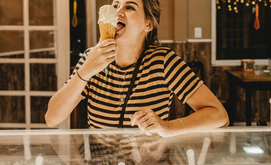 Woman eating ice cream cone in ice cream shop